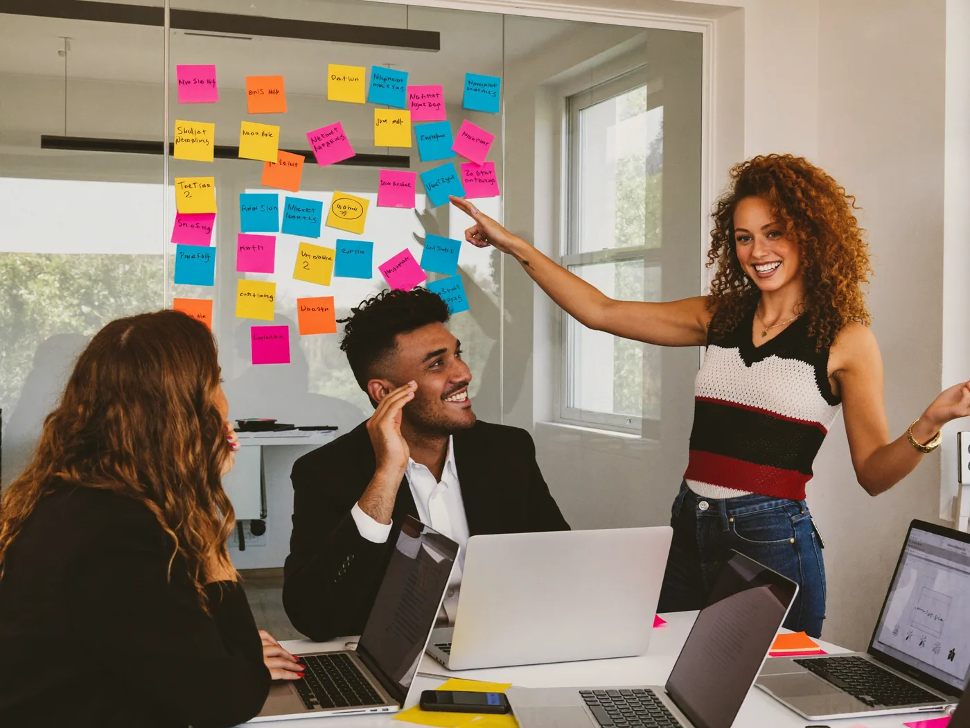 Ragazzo che presenta il suo lavoro ai colleghi davanti a una parete di post-it