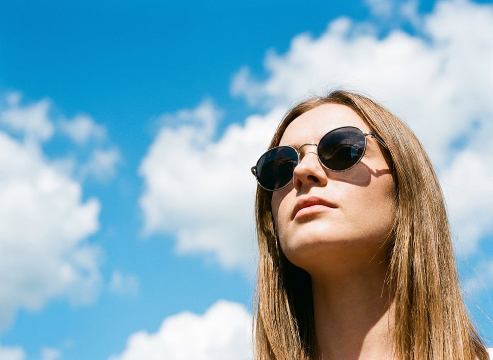 Donna con occhiali da sole sotto il cielo azzurro